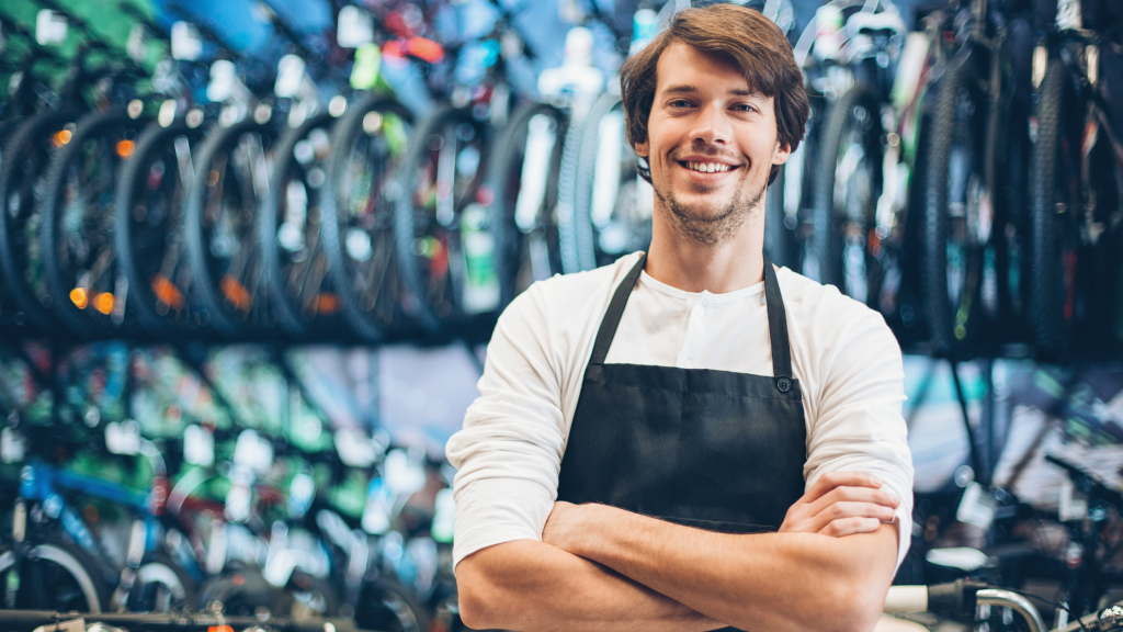 Proprietarul unui atelier de biciclete, zâmbind, cu brațele încrucișate